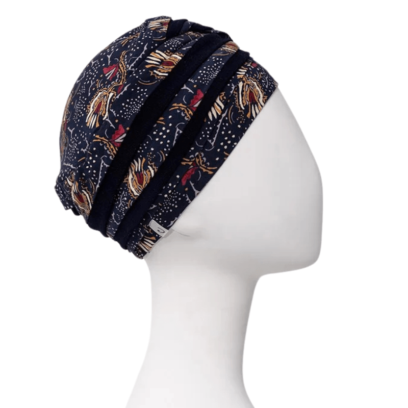 Shanti turban i Amber Garden print set fra højre side på mannequin, med mørkeblå farver og fjer- og stammemotiv