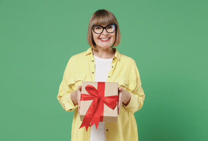 Senior dame står med gave med rødt gavebånd