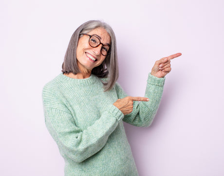Glad ældre kvinde peger på Seniorshops mest populære produkter