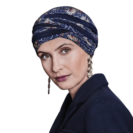 Shanti turban i Amber Garden print båret af kvinde, der viser den mørkeblå hovedbeklædning med fjer- og stammemotiv