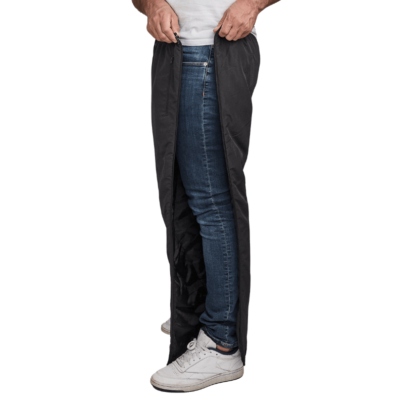 Mand lyner sorte Dobsom termobukser op i siden, over blå jeans og hvide sneakers