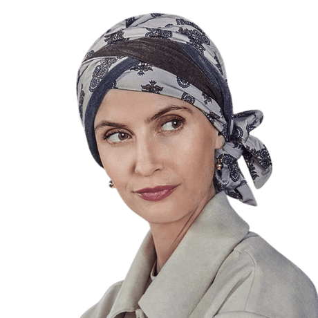 Kvinde med Beatrice turban i paisley-mønster med beige, brun og blå nuancer, bindebånd i siden
