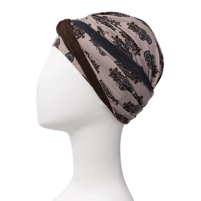 Shakti turban i beige med mørkt paisley-print, set fra siden på mannequin, pandebånd langs nakken